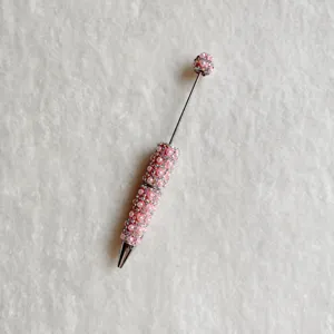 Detail view of a DIY beadable rhinestone pen with pink pearls, sparkling crystals, and metal shaft.