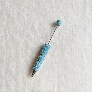 Detailed close-up of the DIY beaded ballpoint pen decorated with blue pearls and sparkling crystals.