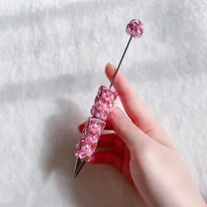 Primo piano dettagliato della penna a sfera con strass, cristallo a cuore rosa e perle.