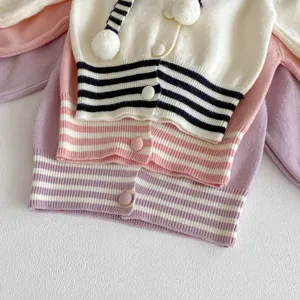 Vista detallada de hermosos cárdigans de punto para bebés con rayas y pompones, tela suave.
