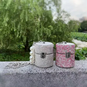 Close-up details of sparkling rhinestone cylinder mini bag with metal lock and pearl chain.