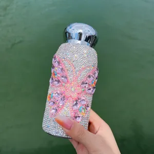 Close-up detail of sparkling rhinestone thermos cup with pink butterfly design and silver cap.