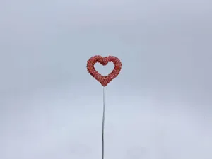 Detail shot of a sparkling rhinestone heart decoration on a metal wire, cute car accessory.