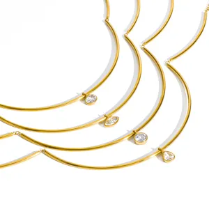 Gros plan détail du collier géométrique en tube incurvé doré avec pendentifs en zircone.