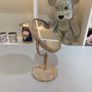 Nahaufnahme eines glitzernden Strass-Tisch-Make-up-Spiegels mit drehbarem Doppelseiten-Design.