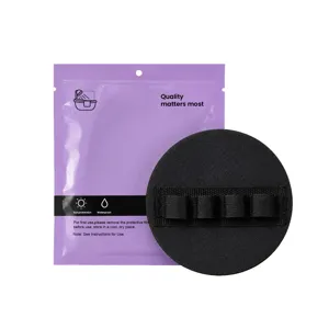 Black round body exfoliating bath sponge with elastic hand strap and purple storage packaging bag.