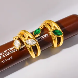 Primer plano detallado de anillos de acero inoxidable chapado en oro de 18K con dijes de circonita.