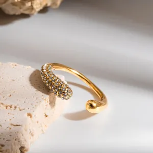 Nahaufnahme eines stilvollen vergoldeten offenen Rings mit funkelnden Kristall-Akzenten.