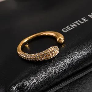 Nahaufnahme eines vergoldeten offenen Rings mit funkelnden Zirkonia-Steinen auf schwarzem Display.