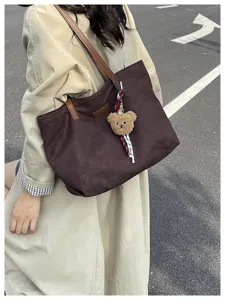 Stylish large capacity brown canvas tote bag with cute bear pendant for daily commuting.