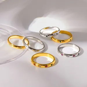 Close-up detail view of multiple stainless steel star-set colored zircon rings on a white surface.
