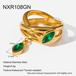 Detalle de anillo de oro de acero inoxidable con hermosas piedras de circonita verde y dije.