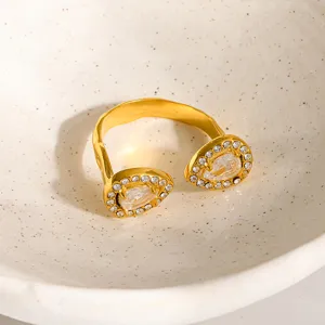 Gedetailleerde opname van vergulde roestvrijstalen open ring met sprankelende druppelzirkonia.