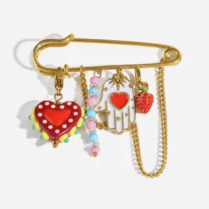 Gros plan détaillé d'une broche épingle de sûreté dorée avec breloques cœurs en acrylique.