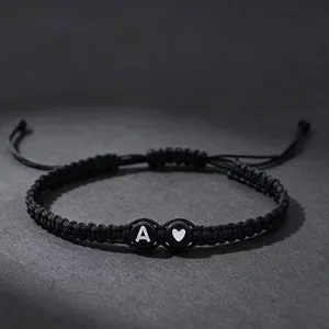 Gedetailleerde close-up van een handgemaakte zwarte gevlochten armband met letterkralen.