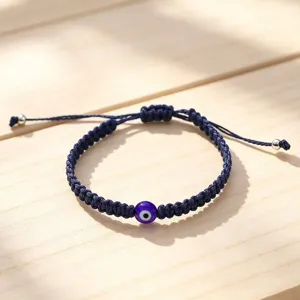 Evil eye bracelet detail close up, blue handmade woven rope with charming nazar bead.