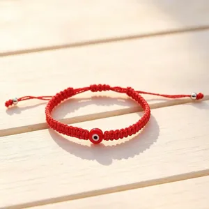 Close-up detail of handmade red string braided evil eye bracelet with adjustable metal closure.