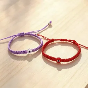 Adjustable handmade braided rope bracelets featuring evil eye charms in purple and red.