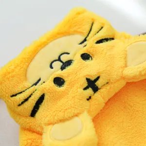 Close-up of cute yellow plush pet costume detail showing embroidered animal face and soft fabric.