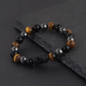 Close-up detail of natural tiger eye obsidian hematite beaded bracelet with engraved bead.