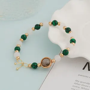Close-up view of the beaded bracelet featuring green malachite-style and white crystal beads.