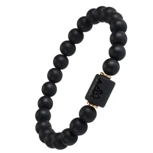 Matte schwarze Achat Perlenarmband mit Zylinderanhänger und goldenen Abstandshaltern.