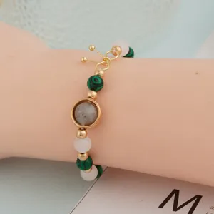Exquisite women beaded bracelet detail shot, green and pink stones with gold clasp.