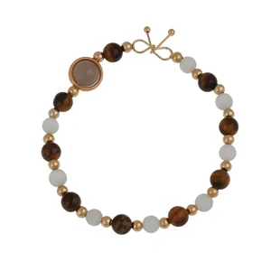 Detail shot of fashion beaded bracelet with brown and white stones and golden metal accents.