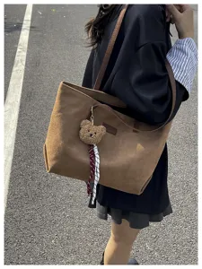 Detail view of the stylish brown suede tote bag featuring a cute fuzzy bear pendant charm.