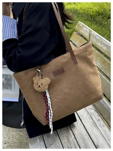 Stylish brown suede tote bag with cute bear charm, perfect for daily commuting and casual use.