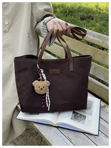 Classic brown canvas tote bag with chic teddy bear pendant, spacious casual shoulder bag.