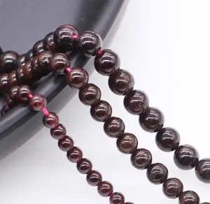 Natural garnet gemstone beads detail shot showcasing the polished wine red round shape.