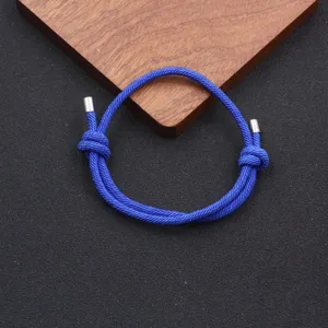 Close-up detail of blue braided rope bracelet with adjustable knot and metal tips.