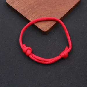Detailed close-up shot of the handmade red nylon parachute cord bracelet with adjustable knots.