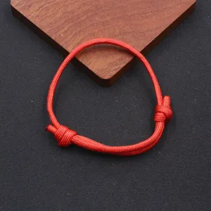 Detailed shot of a red nylon parachute cord bracelet, featuring handmade adjustable woven design.