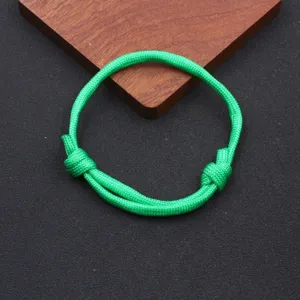 Green nylon paracord bracelet close-up, simple handmade adjustable woven rope detail view.