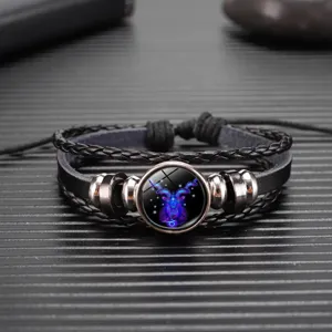 Detalle de pulsera de cuero negro trenzado con colgante de cristal del signo Capricornio.