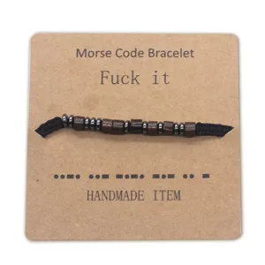 Handmade Morse code beaded bracelet with adjustable black string and kraft paper display card.