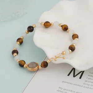 Close-up detail of beaded bracelet featuring tiger eye stones, white beads and golden spacers.