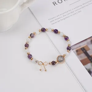 Close-up of beaded gemstone bracelet featuring amethyst, moonstone, quartz, and cute bow charm.
