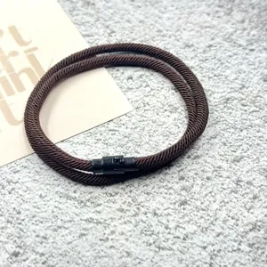 Detail shot of brown braided rope bracelet featuring a sleek black magnetic clasp closure.