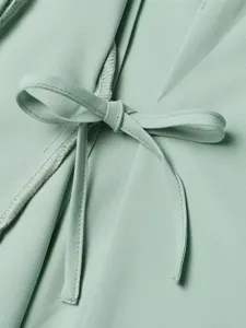 Mintgroene vrouwen blazer strik detail close-up, elegante pak stof textuur foto.
