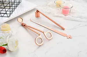 Rose gold candle accessory tool set detail view featuring wick trimmer, snuffer and dipper.