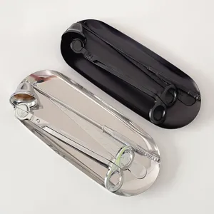 Detailed view of scented candle tool set with wick trimmer, snuffer, dipper and metal tray.