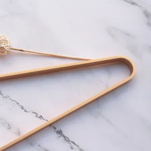 Close-up detail of golden aluminum alloy clothes hanger with flat wire design on marble.