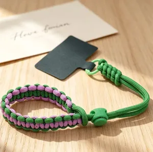 Detailed view of green and purple woven phone wrist strap with adjustable buckle and tether tab.