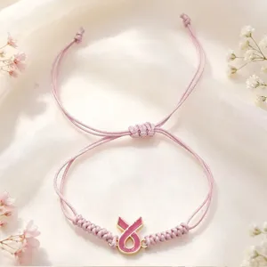 Bracelet cordon tressé rose fait main avec pendentif ruban, design délicat et élégant.