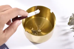 Modern minimalistische gouden roestvrijstalen asbak detailopname voor thuisdecoratie.