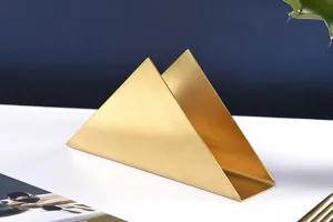 Gold stainless steel triangle napkin holder detail, elegant metal table organizer for cafe and home.