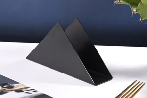 Detailed view of the modern black triangle metal napkin holder on white table, chic.